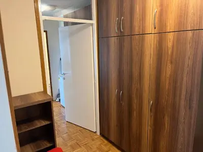 a closet with wooden cabinets and a white refrigerator at Comfort & Style Panoramic Urban Retreat in Novi Beograd