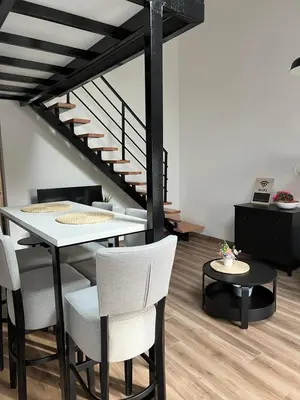a dining room with a table and chairs and a staircase at Apartment Magnolia gallery in Zemun