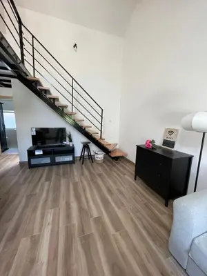 a living room with wooden floors and a staircase at Apartment Magnolia gallery in Zemun