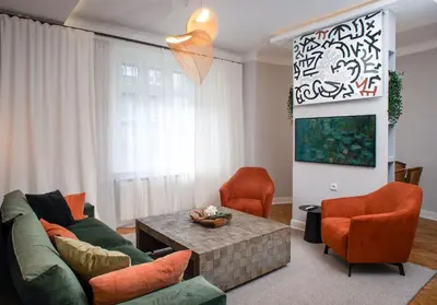 a living room with a green couch and orange chairs at Pop's Apartments in Belgrade