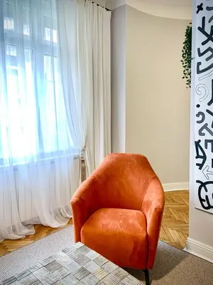 an orange chair in a room with a window at Pop's Apartments in Belgrade