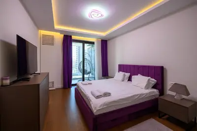a bedroom with a purple bed and a television at Luxury apartment with Pool&Gym in Belgrade