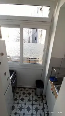 a small kitchen with a window and a tiled floor at Stan na dan Beograd in Karaburma
