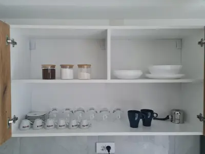 a white shelf with cups and dishes on it at Marash apartman - stan na dan in Belgrade