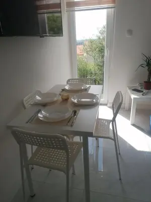 a dining room table with chairs and plates and a window at Marash apartman - stan na dan in Belgrade