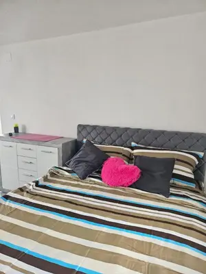 a bedroom with a bed with a pink pillow at MM apartman in Mladenovac