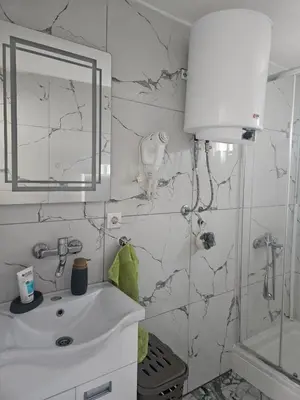 a white bathroom with a sink and a mirror at MM apartman in Mladenovac
