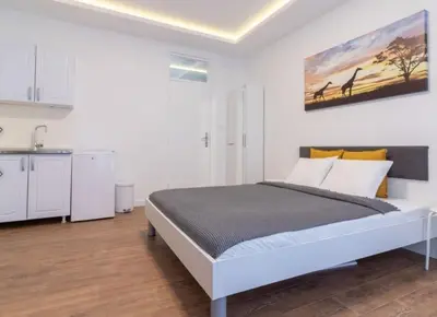 a white bedroom with a bed and a kitchen at yubc in Novi Beograd