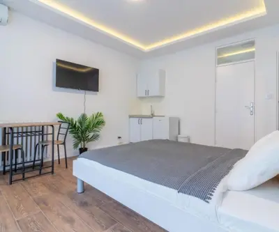 a white bedroom with a bed and a kitchen at yubc in Novi Beograd