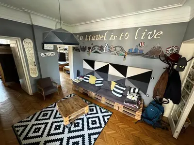 a living room with a table and a sign saying to travel to life at Nomad Hostel in Belgrade