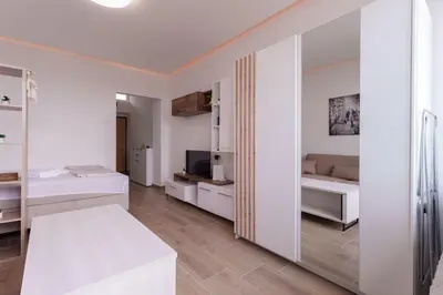 a white room with two beds and a tv at MaKi apartment in Belgrade