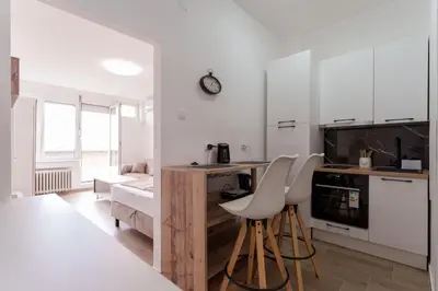 a kitchen with white cabinets and white stools at MaKi apartment in Belgrade