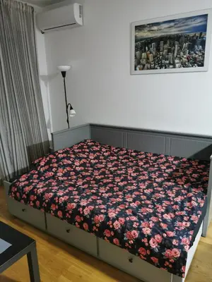 a bedroom with a bed with a floral blanket at Studio Charlie Aviv Park in Mirijevo