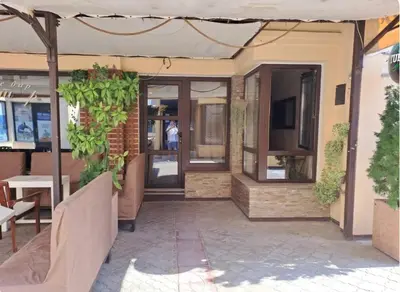 a restaurant entrance with glass doors and plants at Retro studio in Zemun