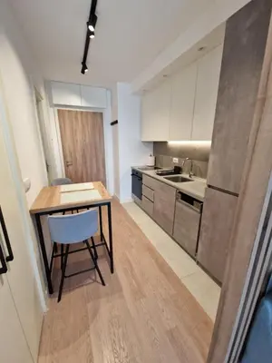 a kitchen with a wooden table and a kitchen with white cabinets at Aqua Royal BW studio in Sajmište