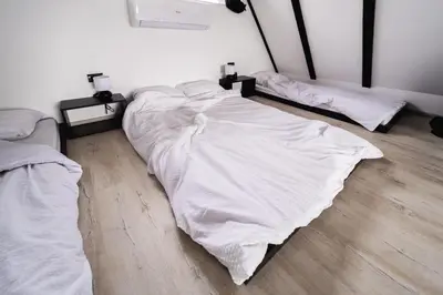 two unmade beds in a room with wooden floors at Ruža vetrova in Mislođin