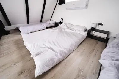 two unmade beds in a room with a wooden floor at Ruža vetrova in Mislođin