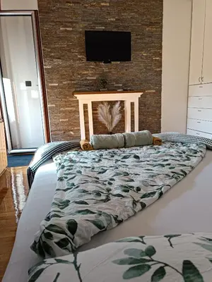 a large bed in a bedroom with a tv on a brick wall at Kutak-Corner in Vračar (historical)