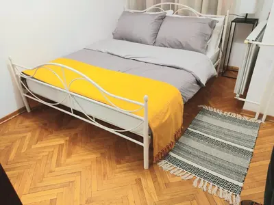a bed with a yellow blanket and a wooden floor at DukeStepa in Belgrade