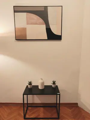 a black table with two plants on it in front of a painting at DukeStepa in Belgrade