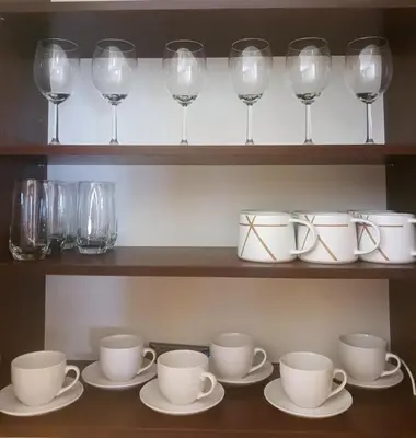 a shelf with cups and saucers and wine glasses at DukeStepa in Belgrade