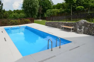 a swimming pool with a bench next to a stone wall at LipaHill SPA in Ripanj