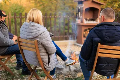 a woman sitting on a chair in front of a fire at LipaHill SPA in Ripanj
