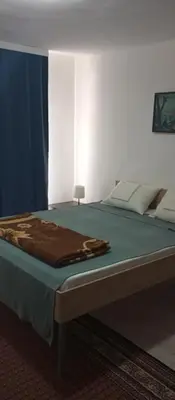 a large bed in a bedroom with a blue curtain at Airport MD Apartment in Belgrade