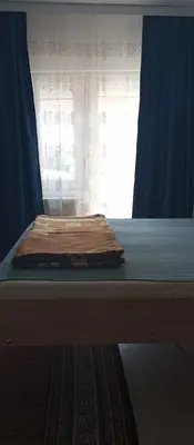 a bed with a blue curtain and a window at Airport MD Apartment in Belgrade