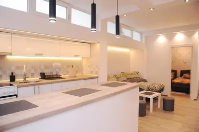 a large kitchen with white cabinets and a living room at 404 Apartment in Belgrade