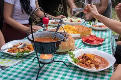 a group of people sitting at a table with food at Čajnički katun-čardak in Grabovac