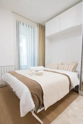 a white bedroom with a large bed with a large window at Apartment - K District Belgrade in Belgrade