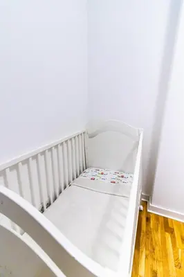 a white crib in a room with a wooden floor at Angelina city LUX apartment with garage in Belgrade