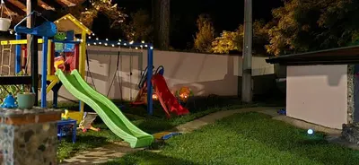 a playground with a slide in a yard at night at Bukuljska svežina 1 in Arandjelovac
