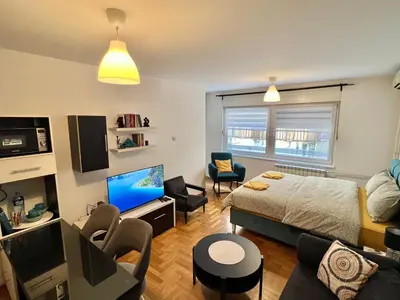 a bedroom with a bed and a living room with a tv at Maison d'Elite in Belgrade