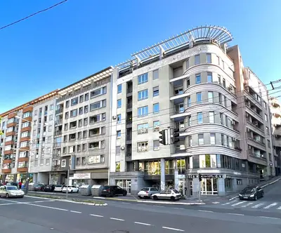 a large white building with cars parked in front of it at Maison d'Elite in Belgrade