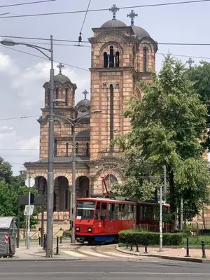 a red bus driving past a building with a tower at Apartment Little Oasis TASH in Belgrade