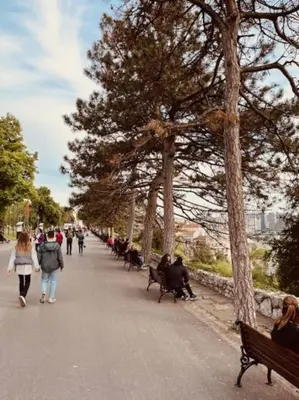 a group of people walking down a street with benches at Lela's Place Vojvode Brane in Belgrade