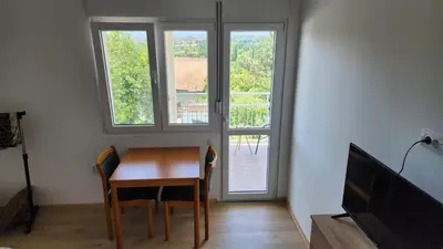 a dining room with a table and two windows at Udobna Soba Sa Prelepim Pogledom #4 in Mladenovac