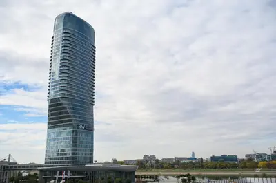 a tall glass building in front of a city at inJoy in Sajmište