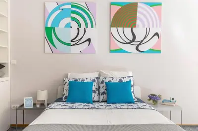 a bedroom with three paintings above a bed with blue pillows at 3 Steps from Center in Belgrade