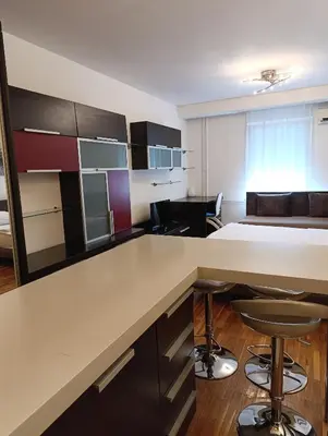 a room with a kitchen with a bed and a desk at Iris Slavija in Sajmište