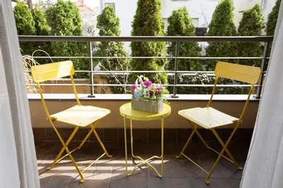 two yellow chairs and a table with flowers on a balcony at Goldy in Belgrade