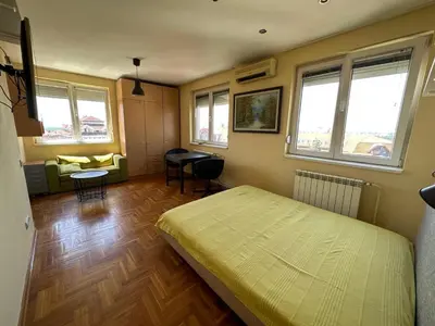 a bedroom with a bed and a living room at apartman Ada mall in Čukarica