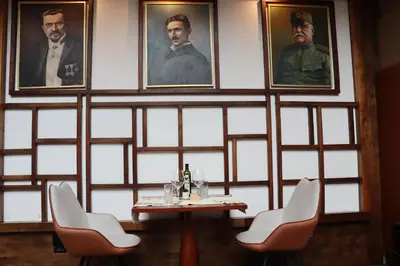 a table and chairs in a room with portraits on the wall at Zepter Hotel Belgrade, member of Zepter Hotels in Belgrade