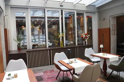 a restaurant with tables and chairs and windows at Zepter Hotel Belgrade, member of Zepter Hotels in Belgrade