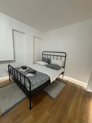 a bed in a room with a white wall at Apartments Sat in Belgrade