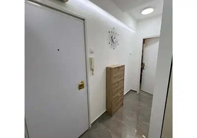 a white hallway with a door and a cabinet at Apartments Sat in Belgrade