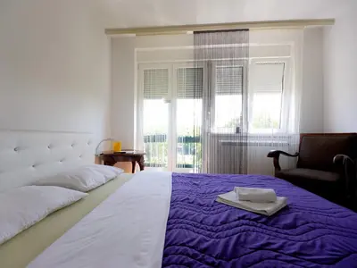 a bedroom with a large bed and a chair at Apartments Sat in Belgrade