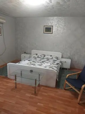 a bedroom with a white bed and a chair at apartman Milica in Ruma